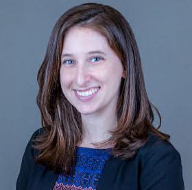 Rebecca Rehr with brown hair and wearing a black coat and blue blouse