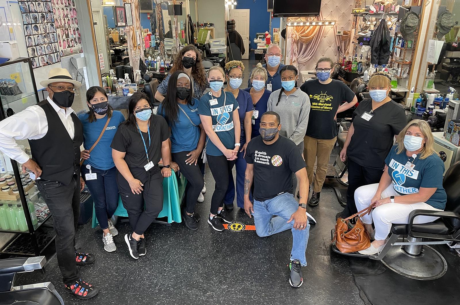 Dr. Stephen Thomas with students, barbers and nurses at the Shop Spa barbershop who are working the vaccine clinic, all are wearing masks