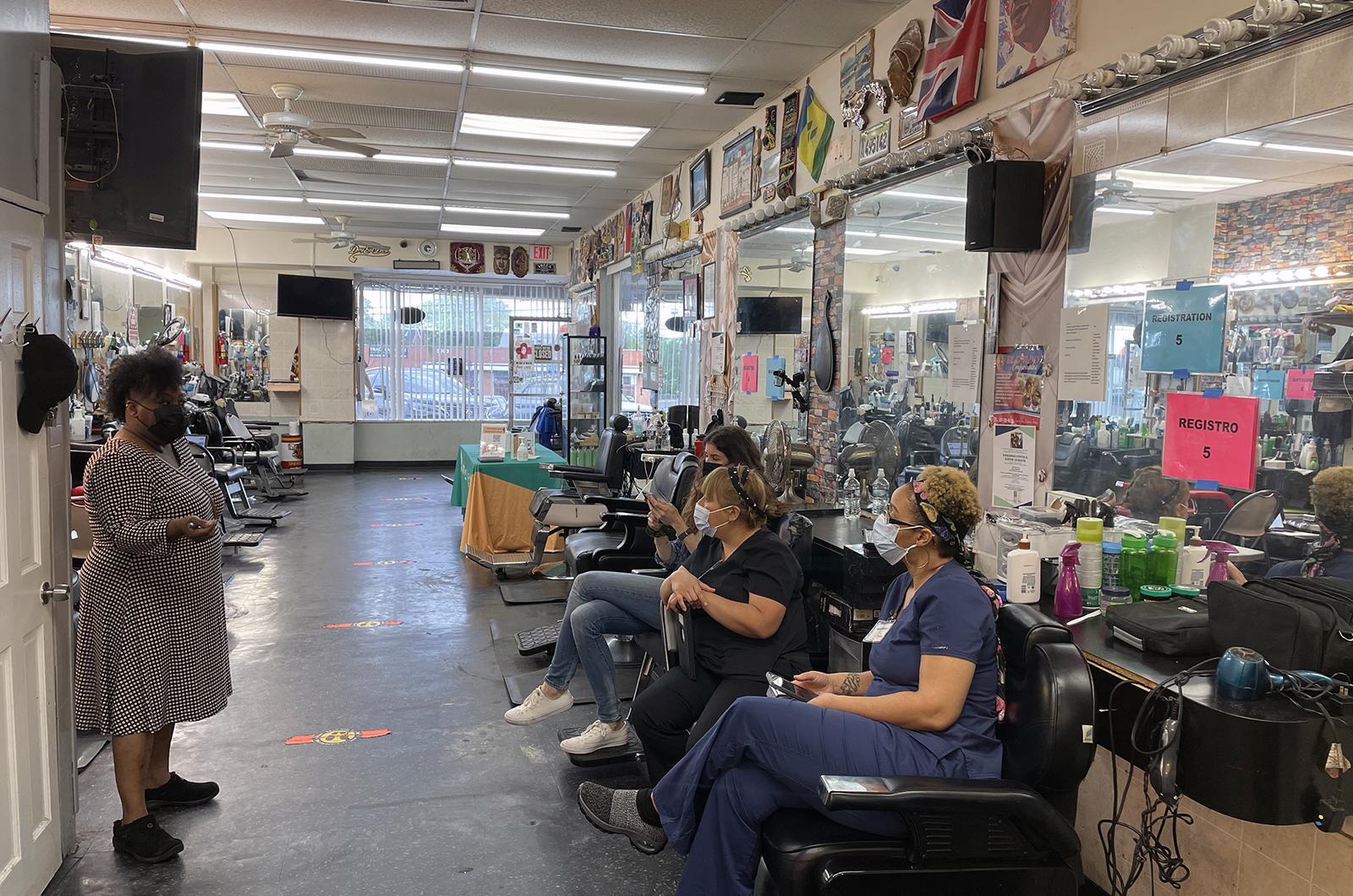 Nurses who administered vaccines at a barbershop clinic sit and talk in the barber chairs.