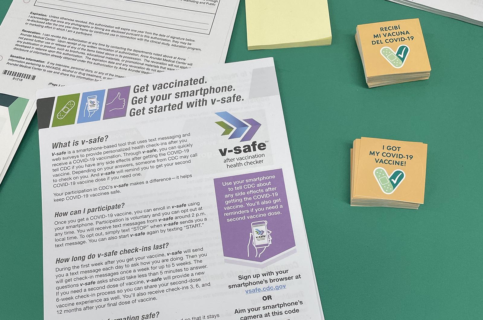 Literature on a table at the barbershop clinic shows how to sign up for the CDC's safe vaccine symptom tracking system.