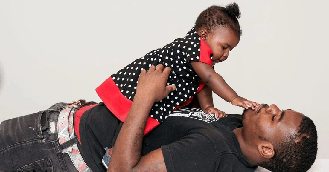 Black father playing with baby girl