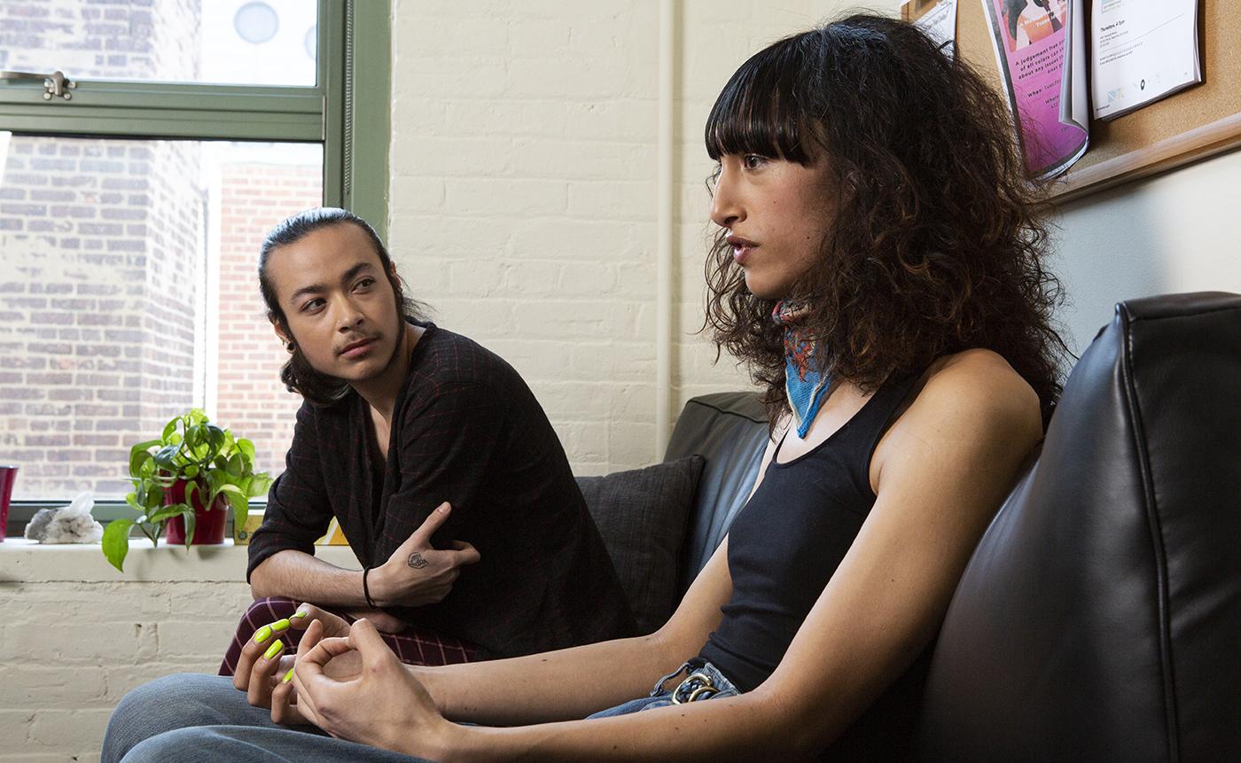  A couple, a genderqueer person and transgender woman, sitting on a therapist's couch and talking