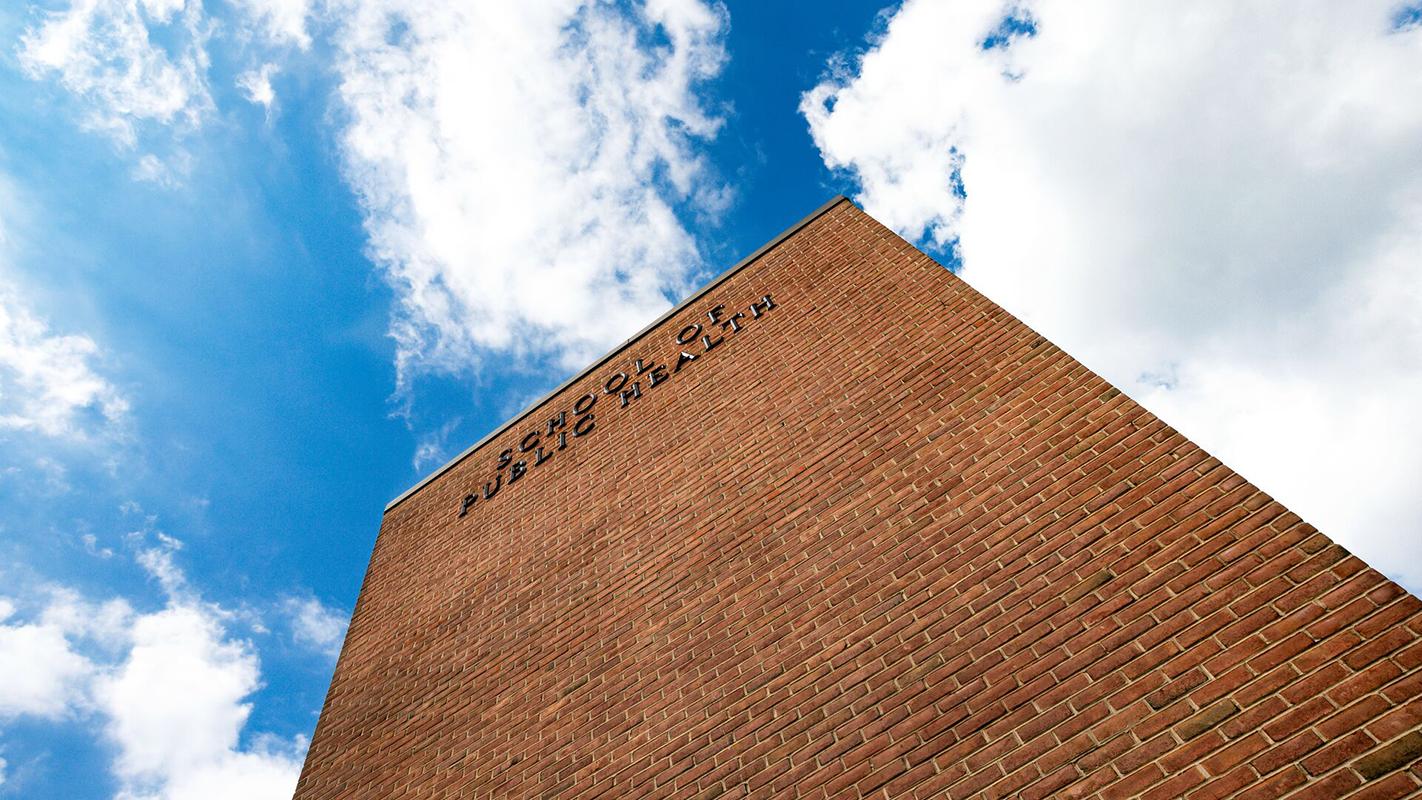 Looking up at the School of Public Health Building with blue sky and clouds above