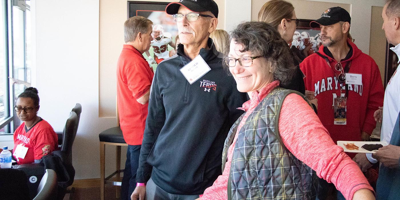 Ayne Furman and Arnold Miller with other Terps dressed in Maryland gear in the football stadium suite