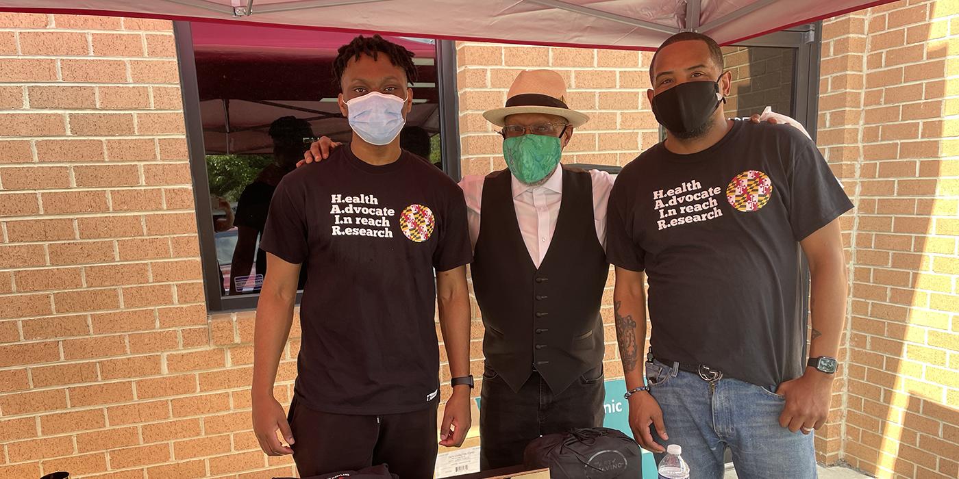 Stephen Thomas with two volunteers with the Health Advocates in Reach and Research program wearing masks at a COVID vaccine clinic at a beauty salon.