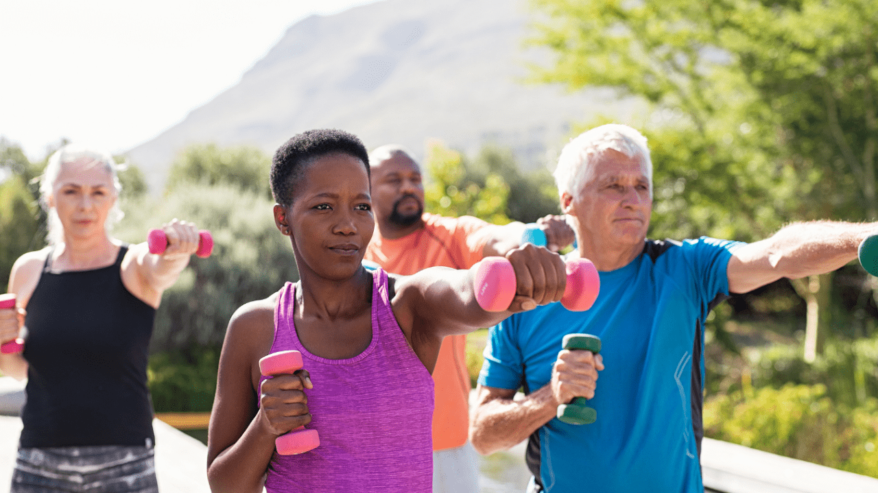 Diverse group of mature adults exercising outside with hand weights