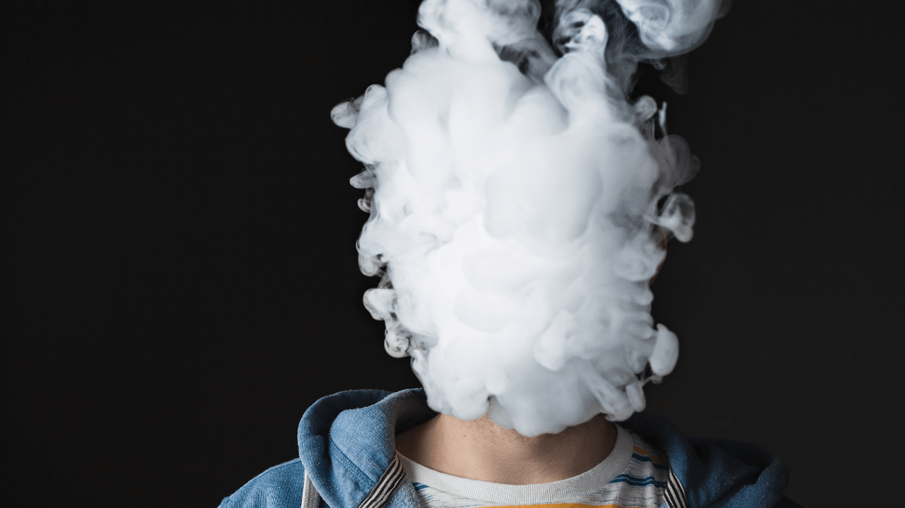 A smoke cloud partly obscures a person's face 