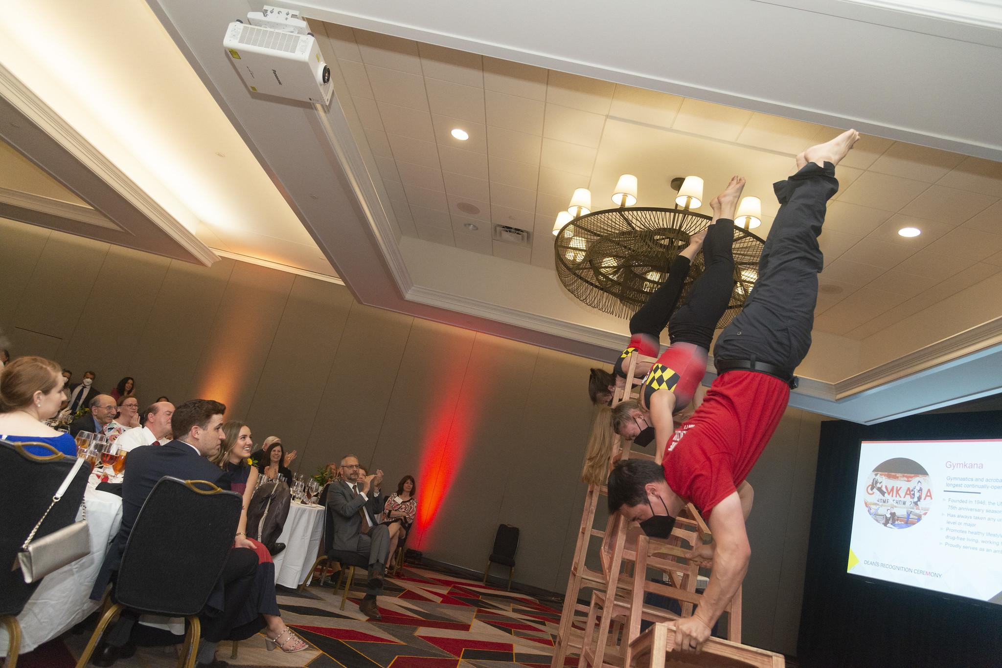 Gymkana troupers perform handstands on chairs