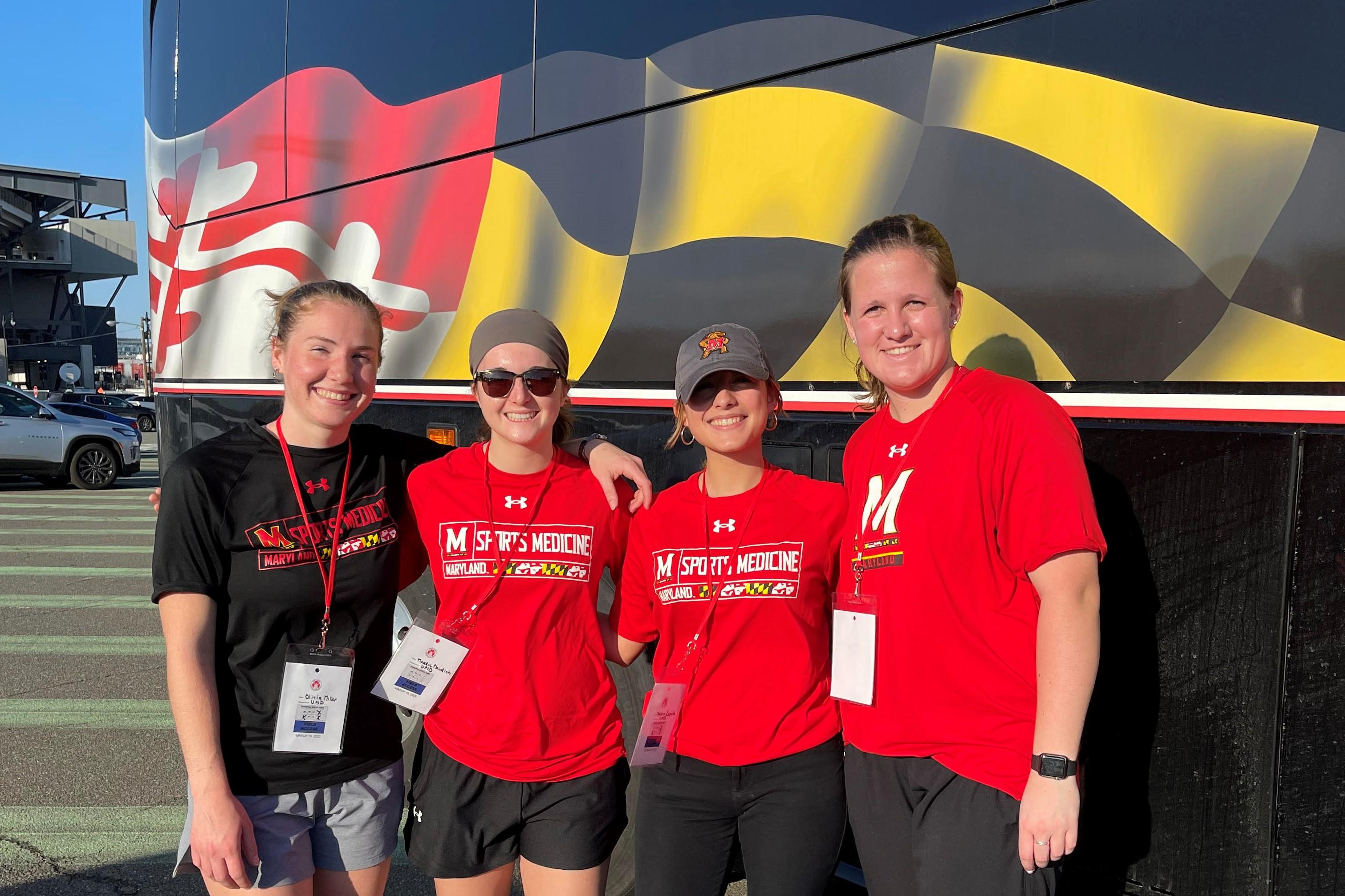 Four students stand together under the Maryland Flag