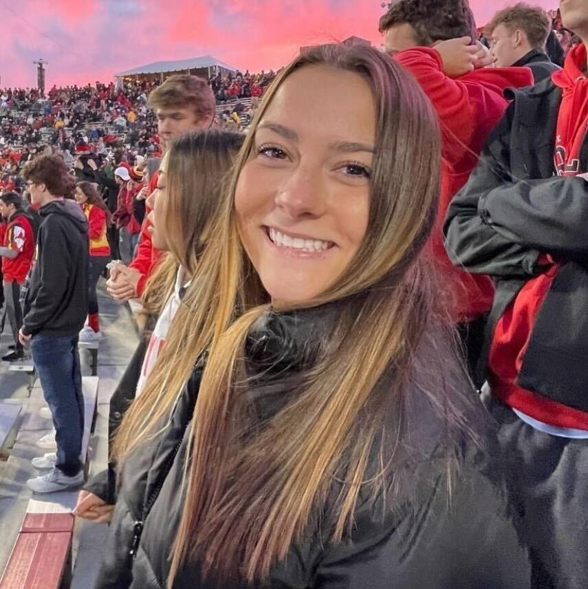 Girl in black jacket with pink clouds behind her