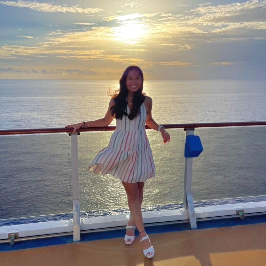 Girl in striped dress standing in front of a sunset