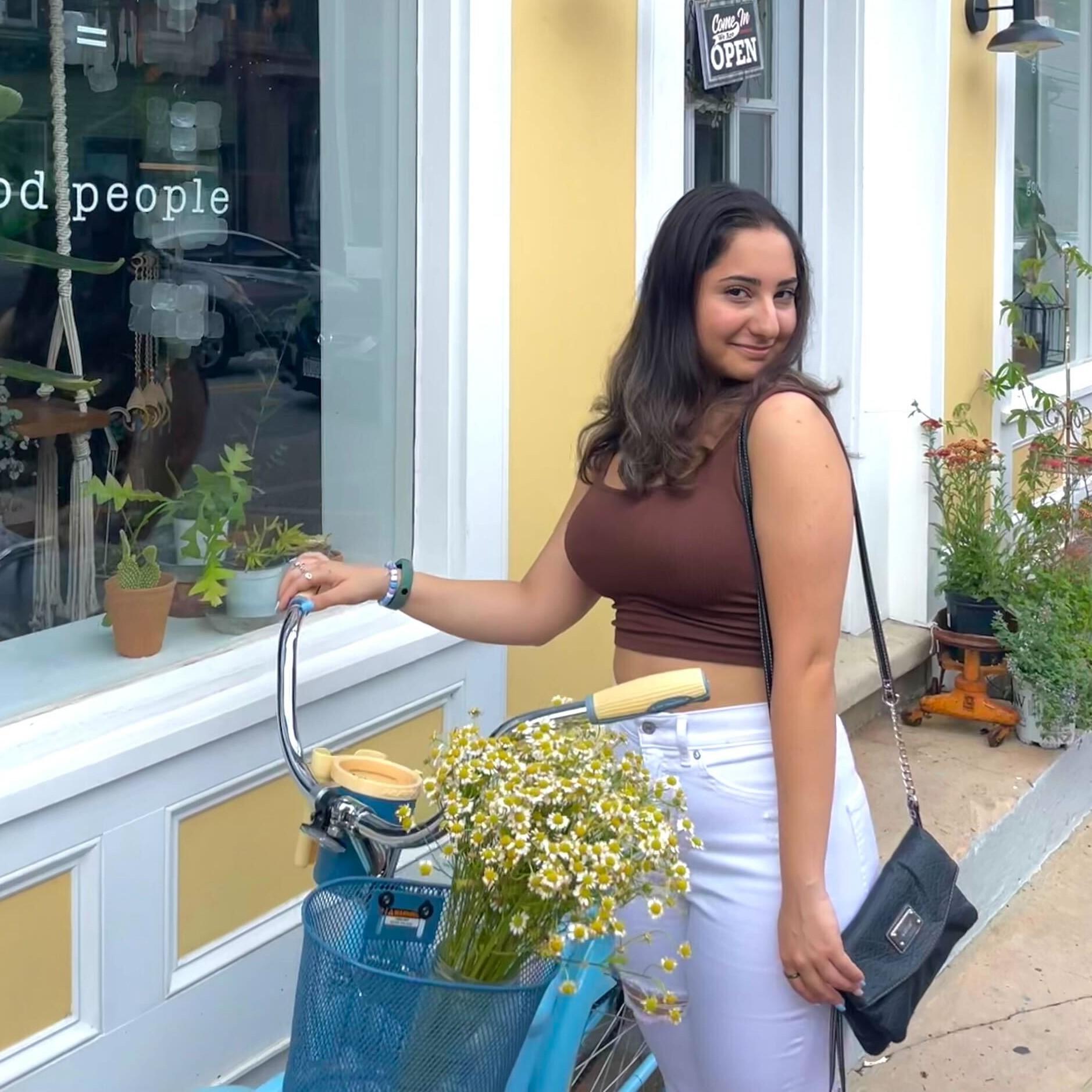 Girl stands by bike with flowers