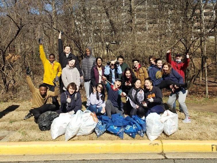 Group of students with filled trash bags in front of them