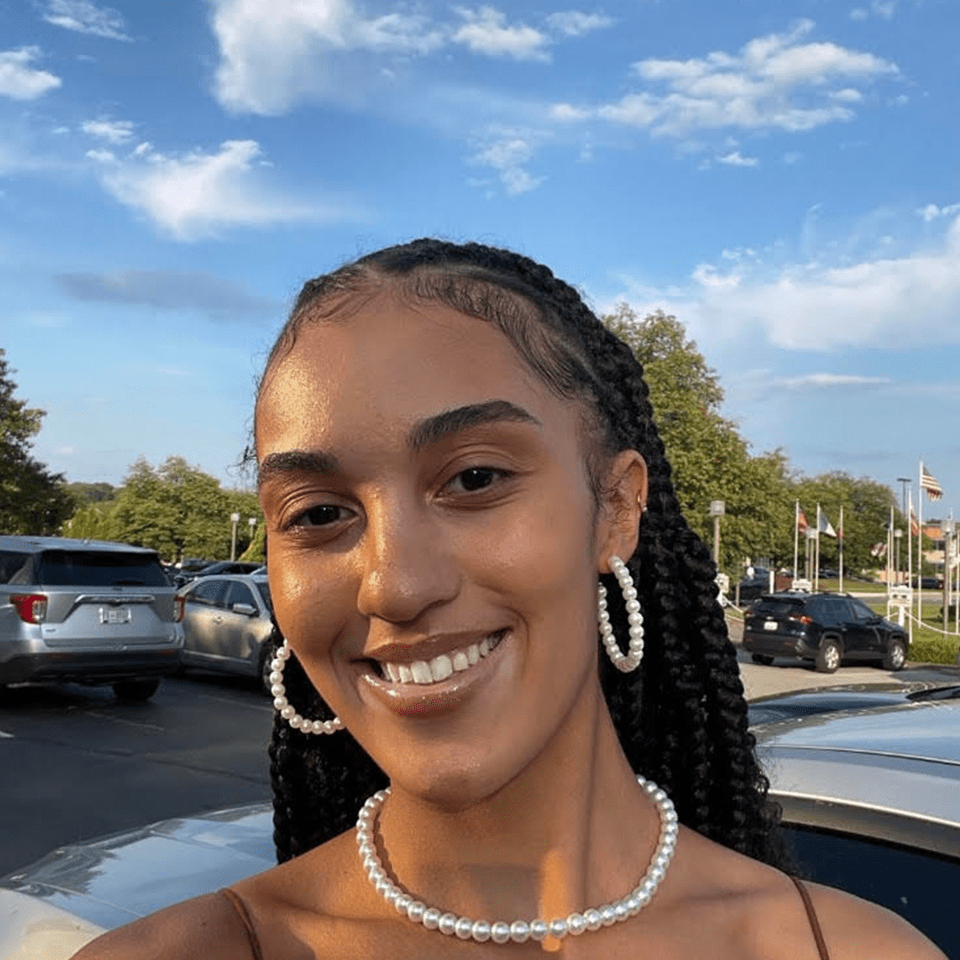 School of Public Health student is smiling, wearing hoops earrings and pearl necklace.