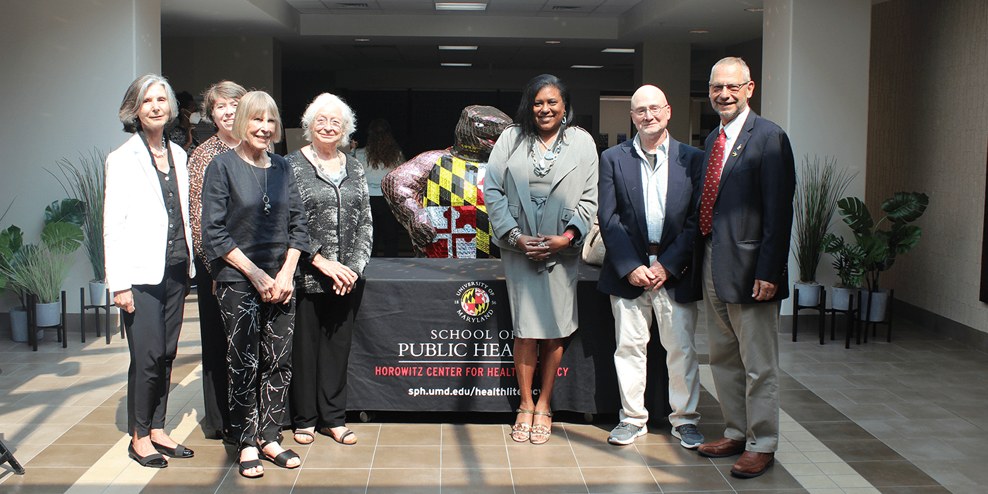 Oral health symposium speakers standing inside the School of Public Health lobby by Testudo statue. 