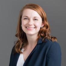 Jameson Roth, young woman, red hair, smiling, wearing navy blue blazer