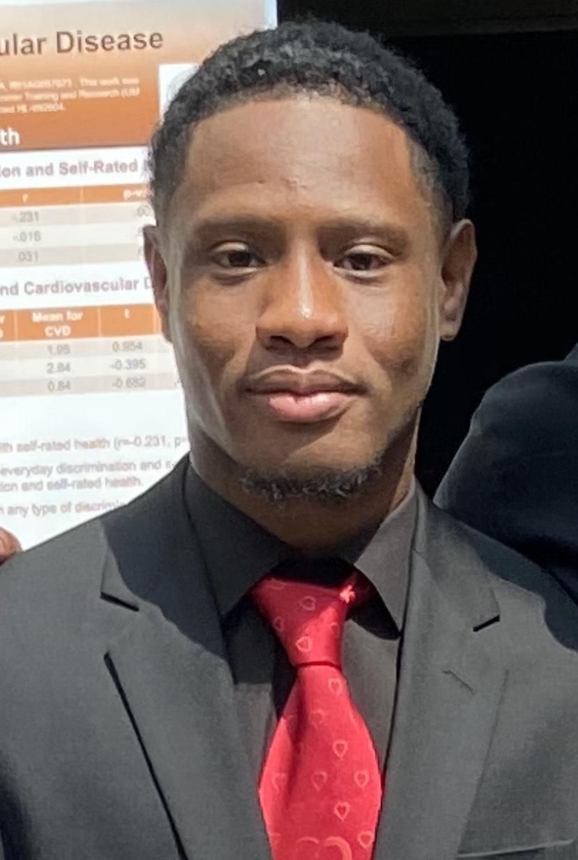 School of Public Health student is wearing a black suit with a red tie. 