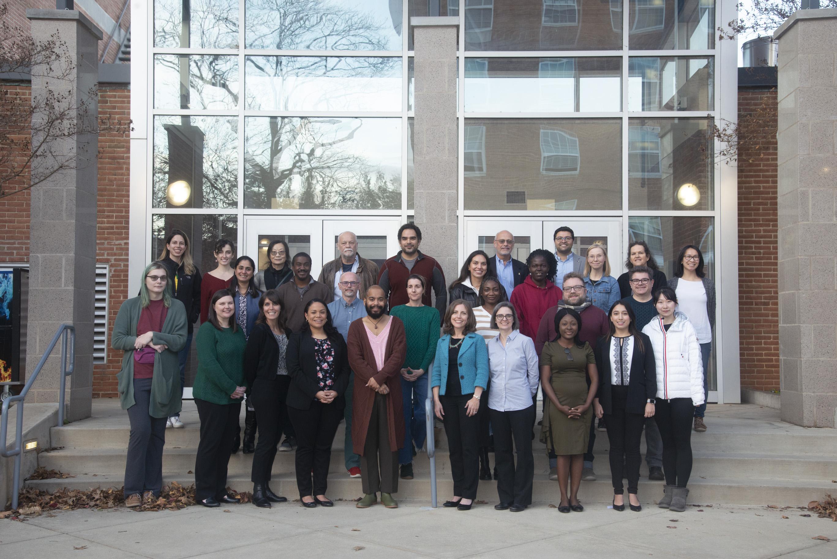 A group of students stand on concrete steps in front of the UMD School of Public Health building.