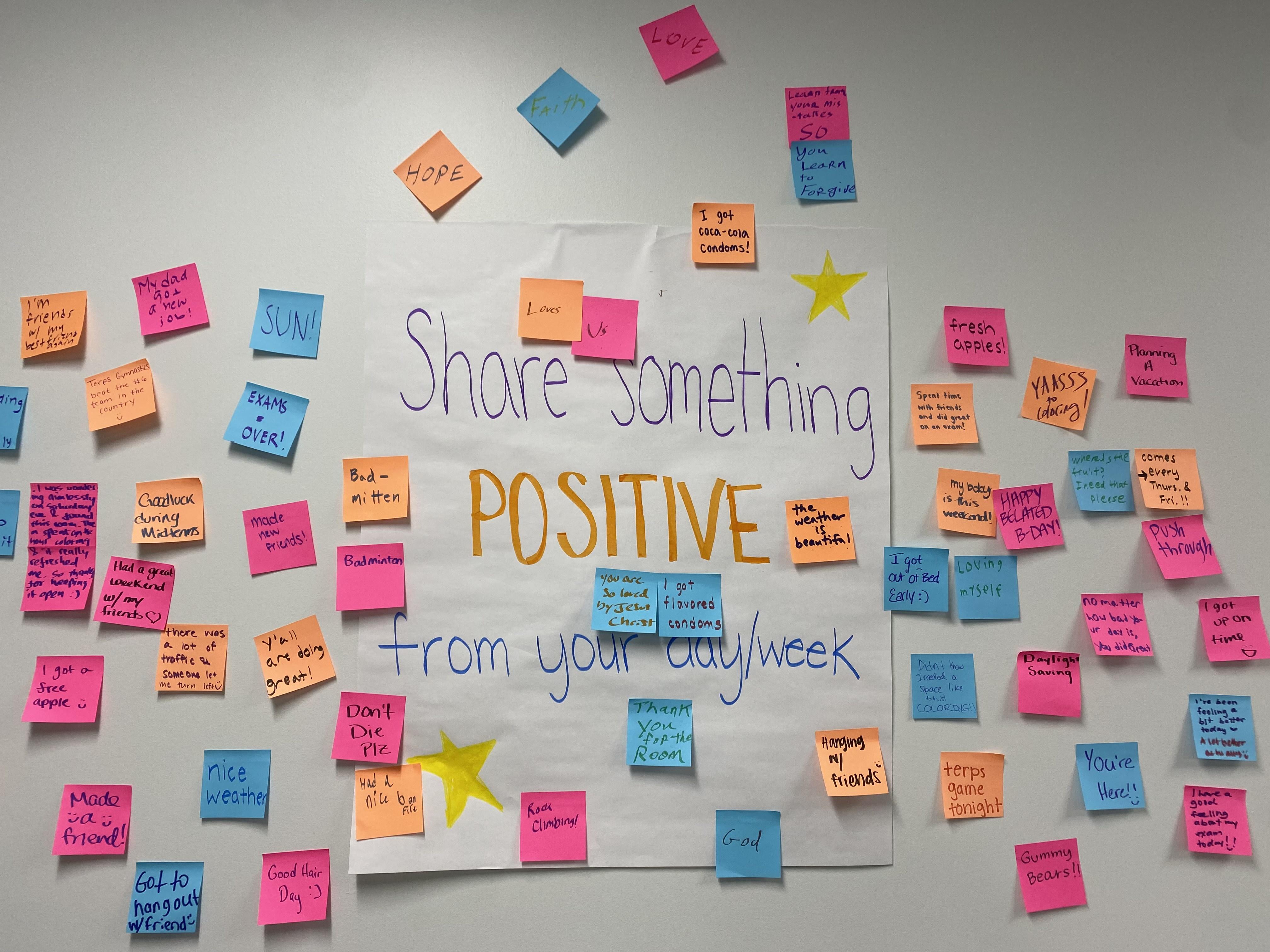 Sign stating "share something positive" and surrounded by post-it notes.