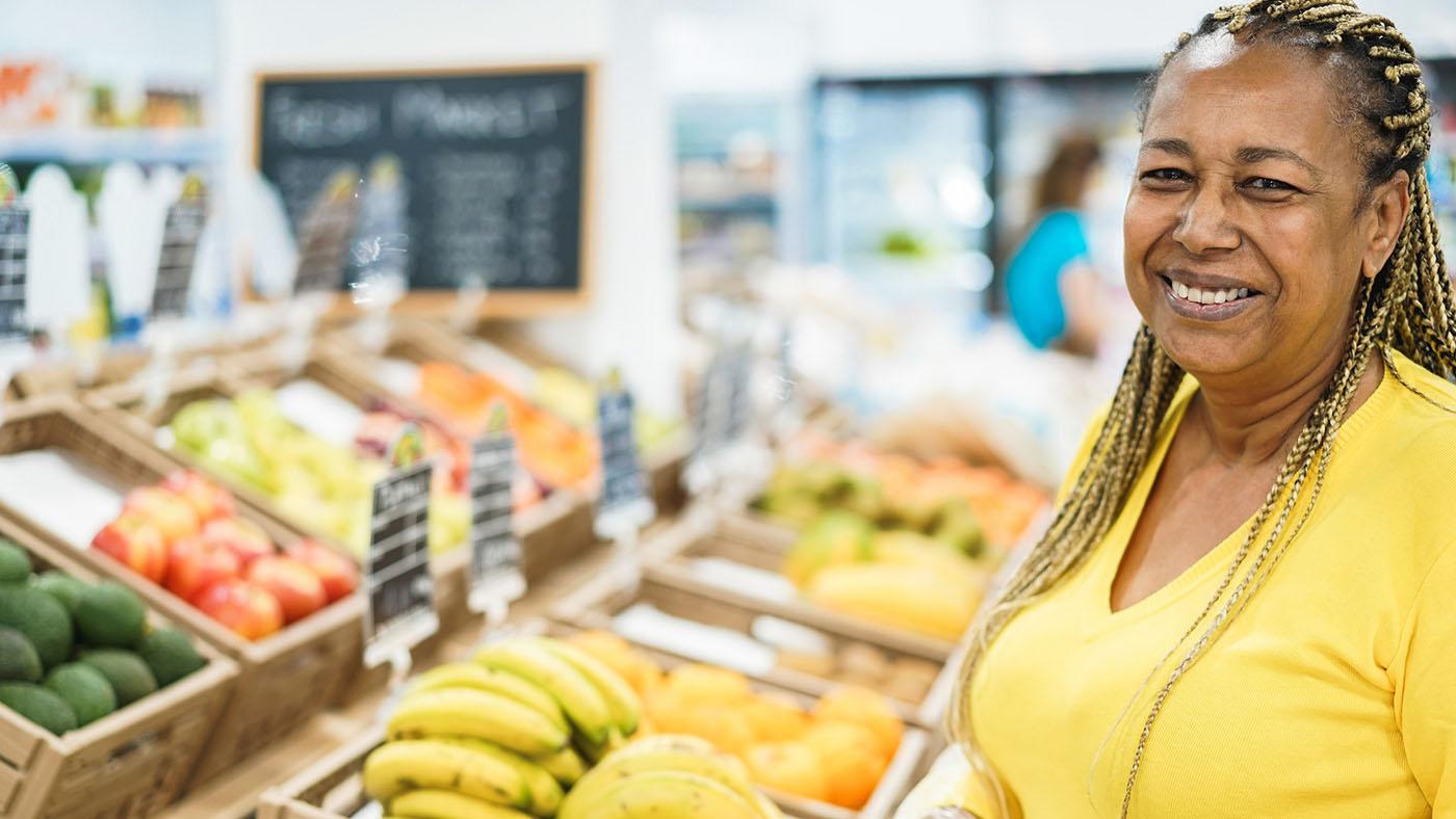 Black female customer buying organic food fruits inside eco fresh market.