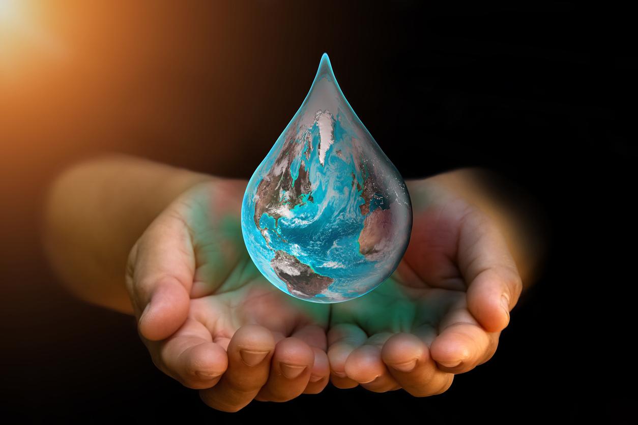 Blue Earth world with dripping water on two hand at wait on abstract black background. 