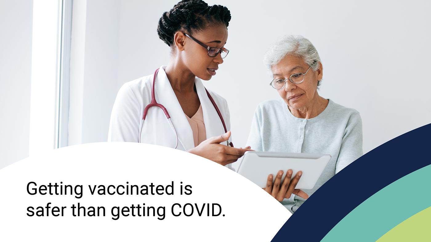 Stock photo of a doctor showing a patient some information on a tablet. Text at the bottom reads "Getting vaccinated is safer than getting COVID"