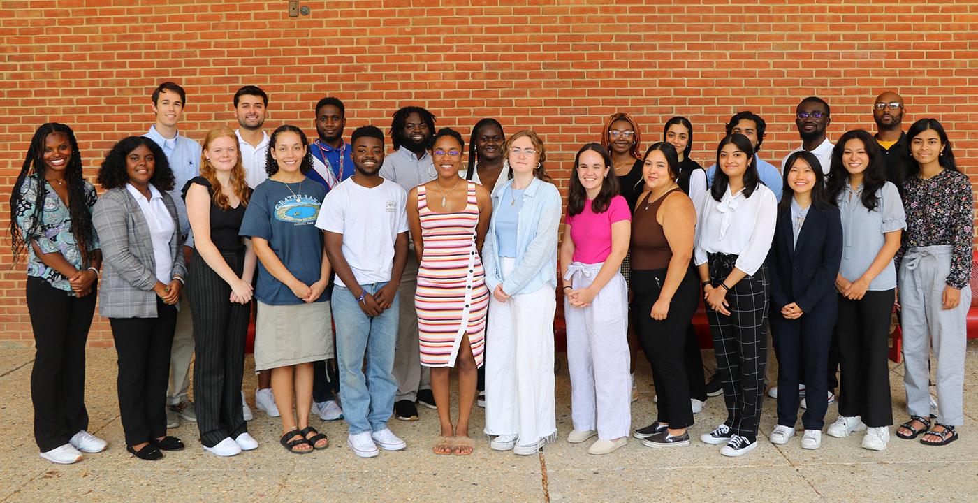 Group of people stand in front of a brick wall outside the School of Public Health.