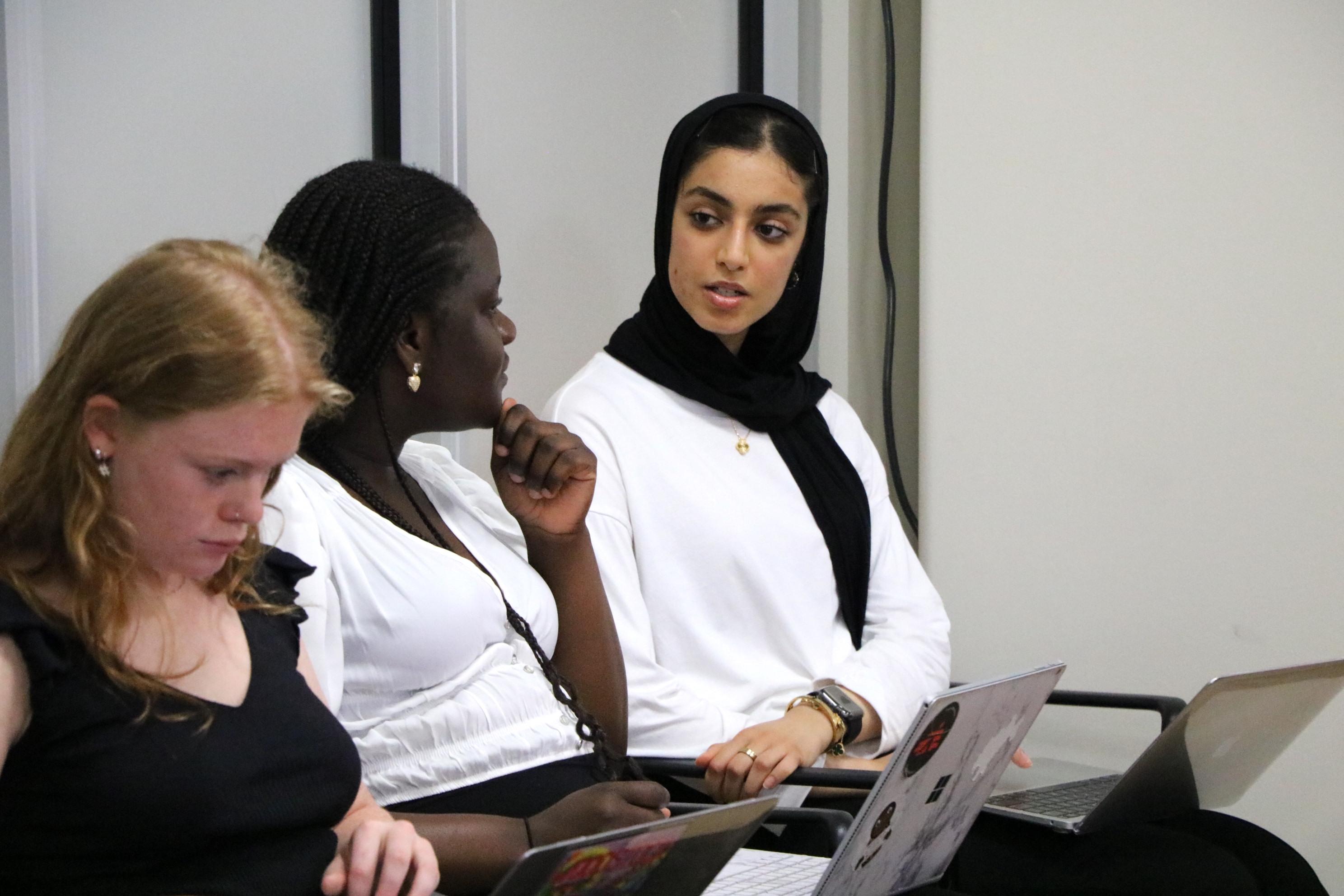 A female student speaks as two others look on.