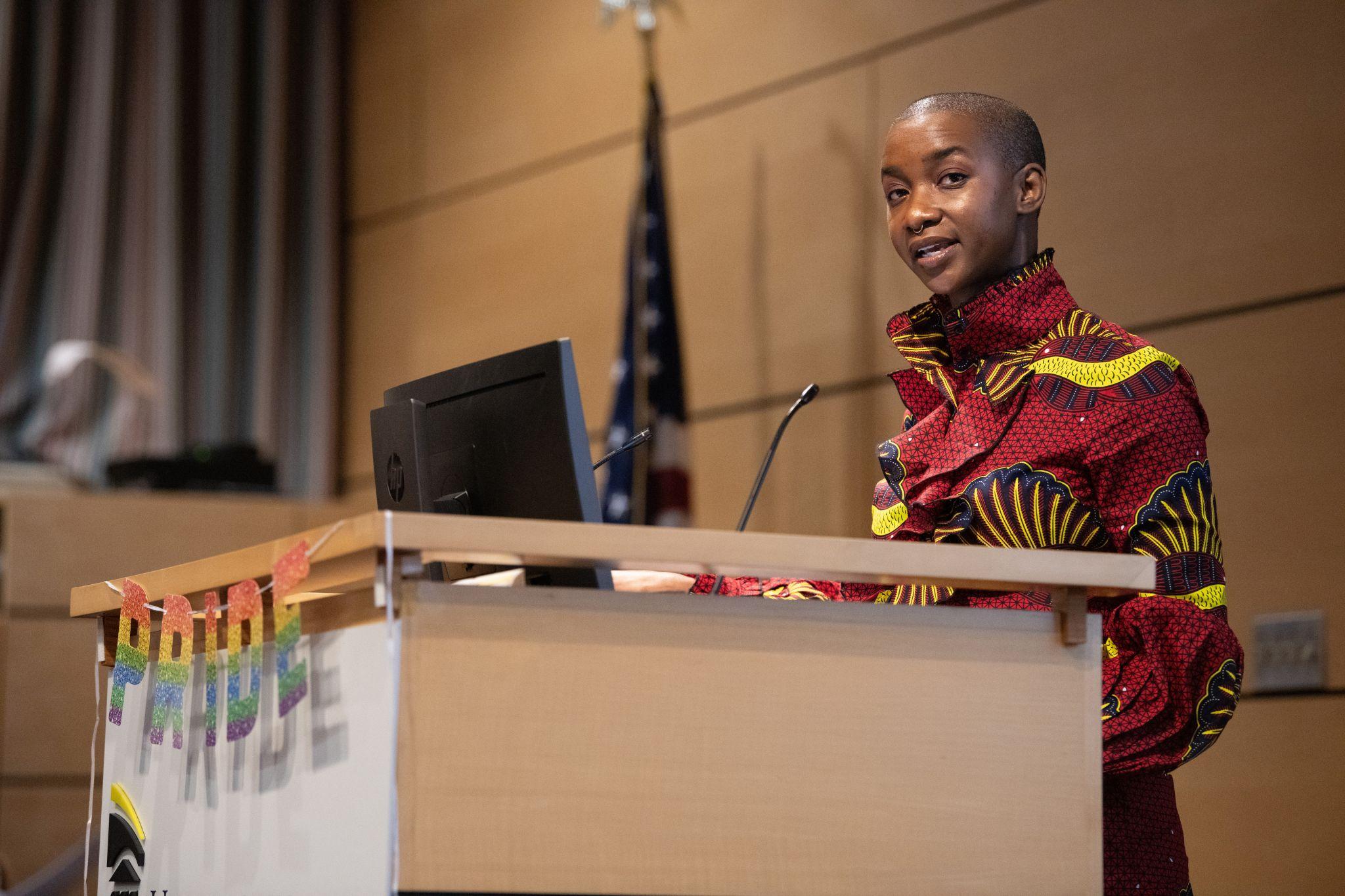 Black non-binary professor speaking at a podium