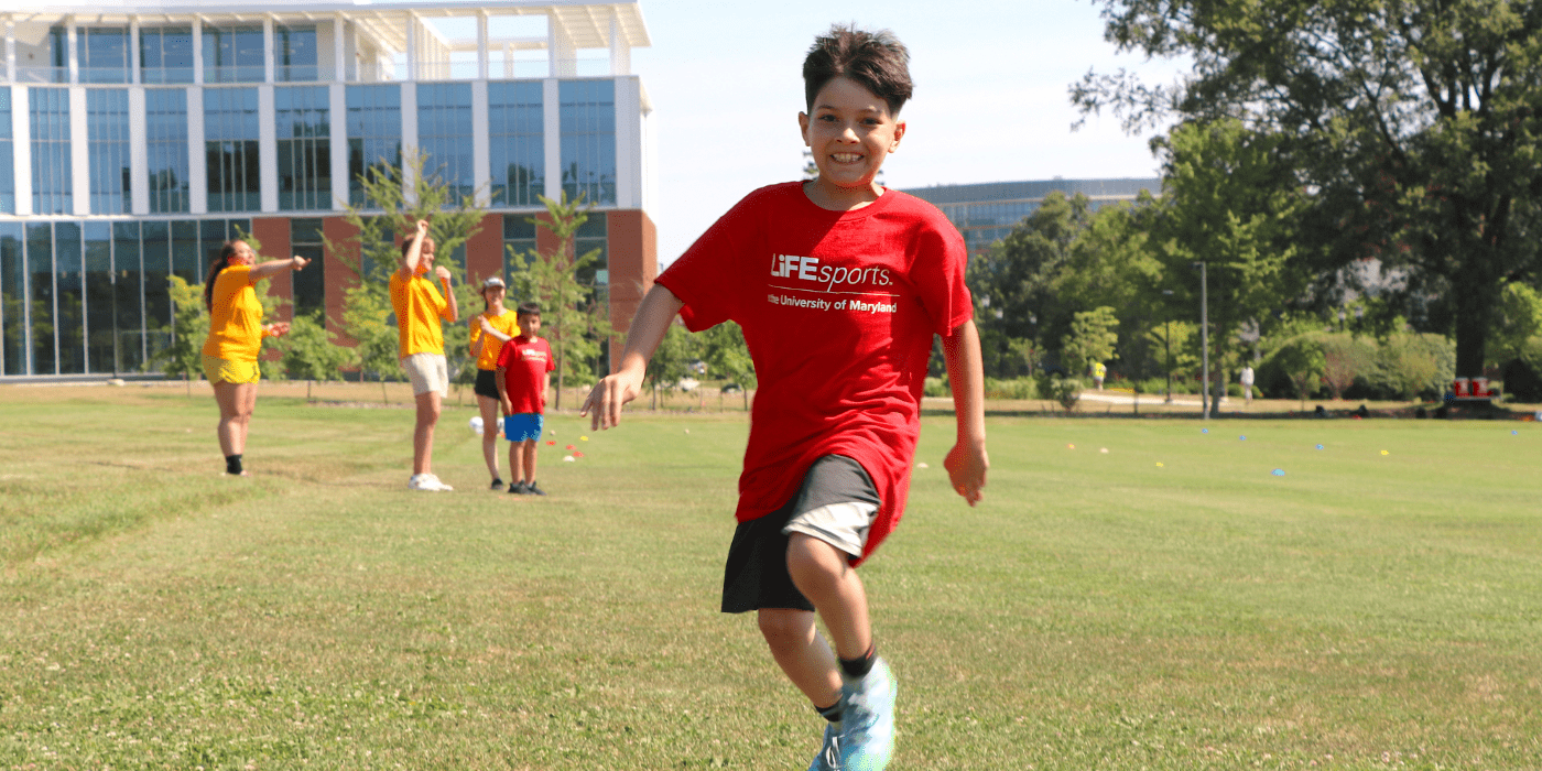 Kid smiling and running to first base in kickball