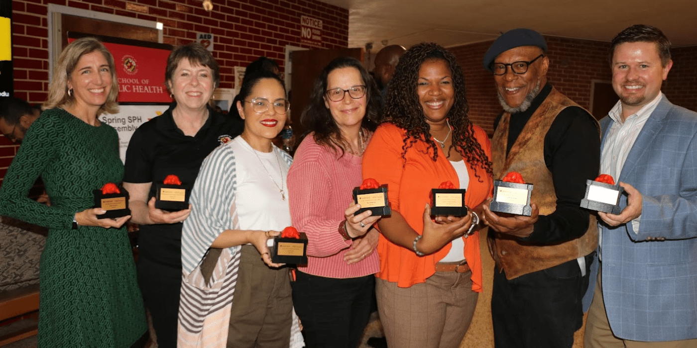 Group of Faculty hold awards and smile at camera