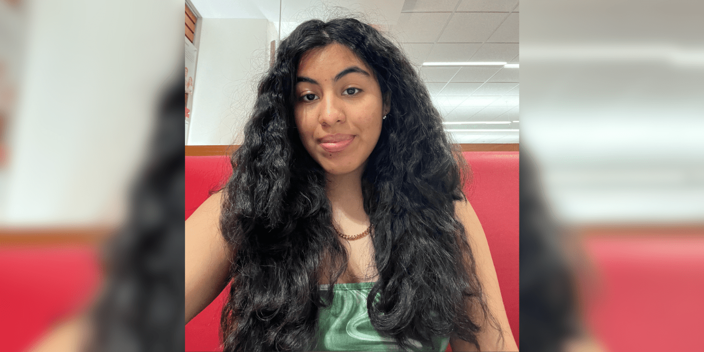 Student with long black hair looks into camera with slight smile