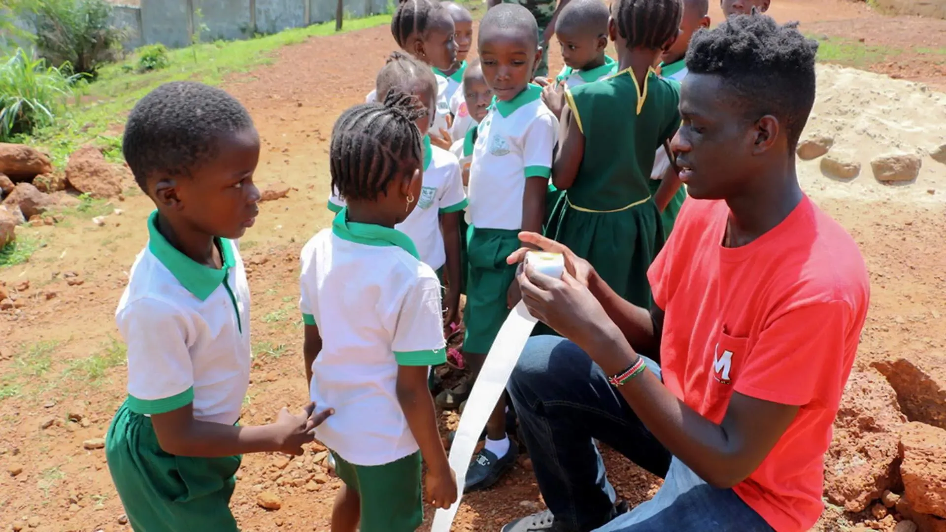 Student volunteer handing little boy a sticker from roll of stickers