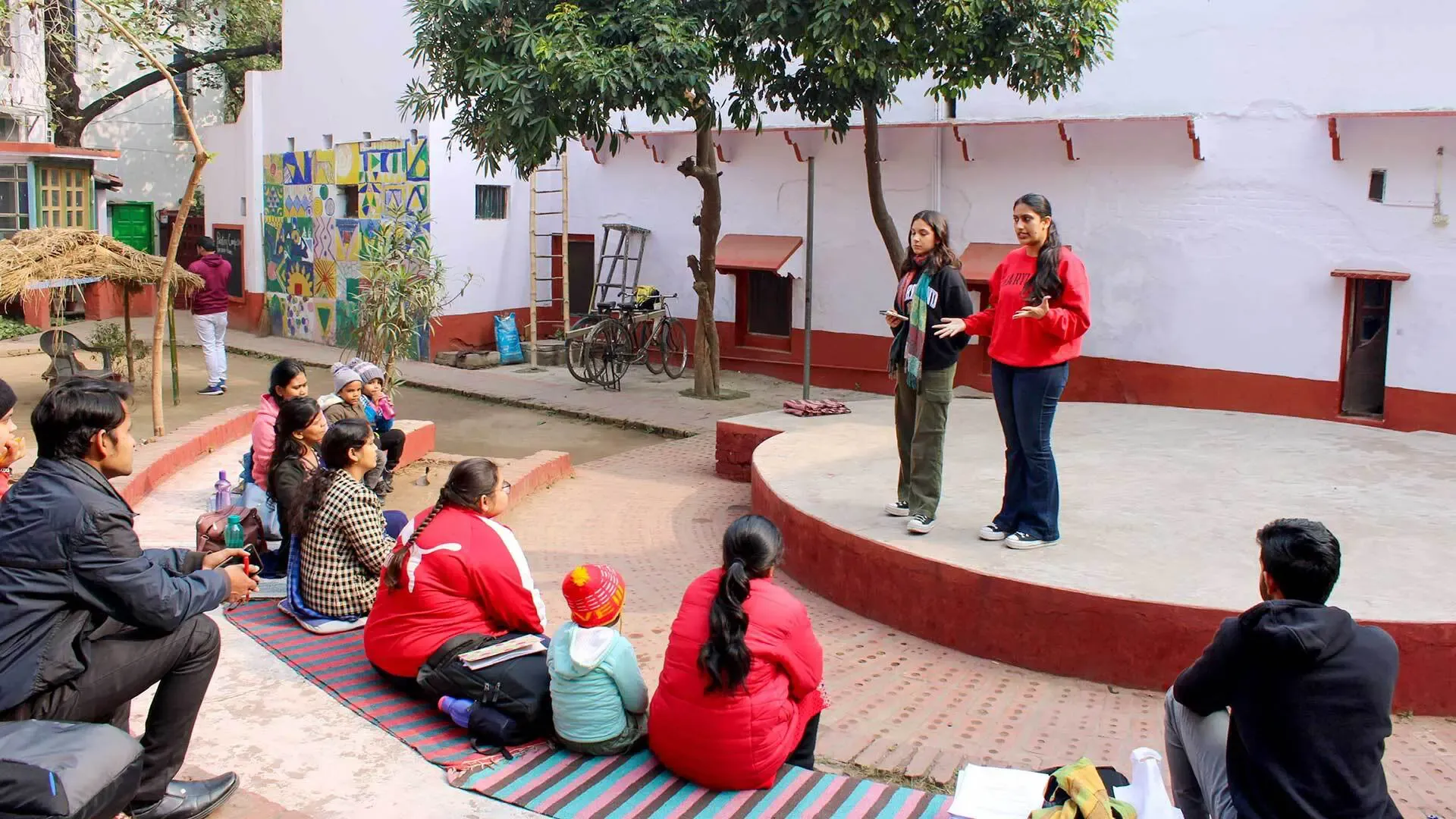 2 students giving a presentation on a circular stage in front of a crowd, in india