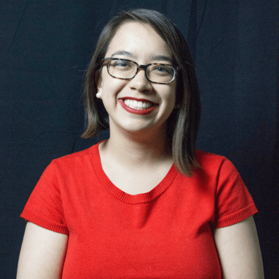 SPH professor smiles to camera wearing red top and glasses