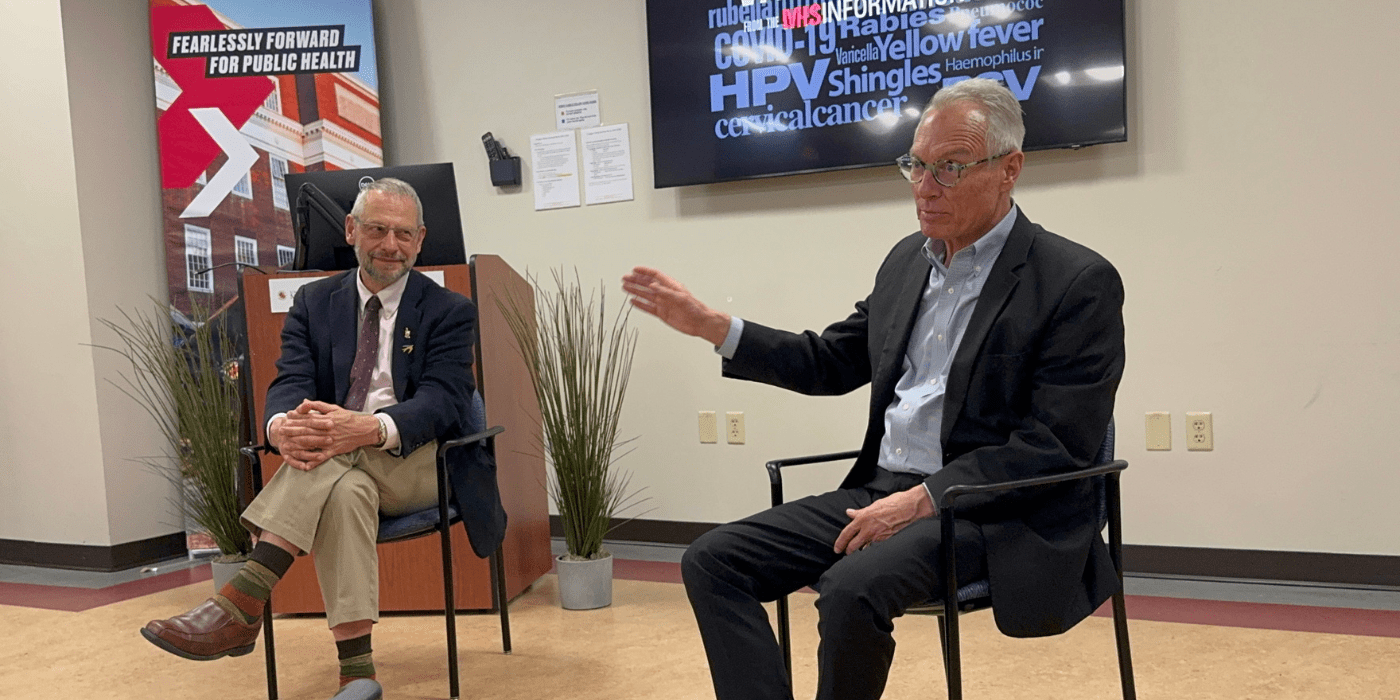 Two men sitting as moderator and speaker to an audience