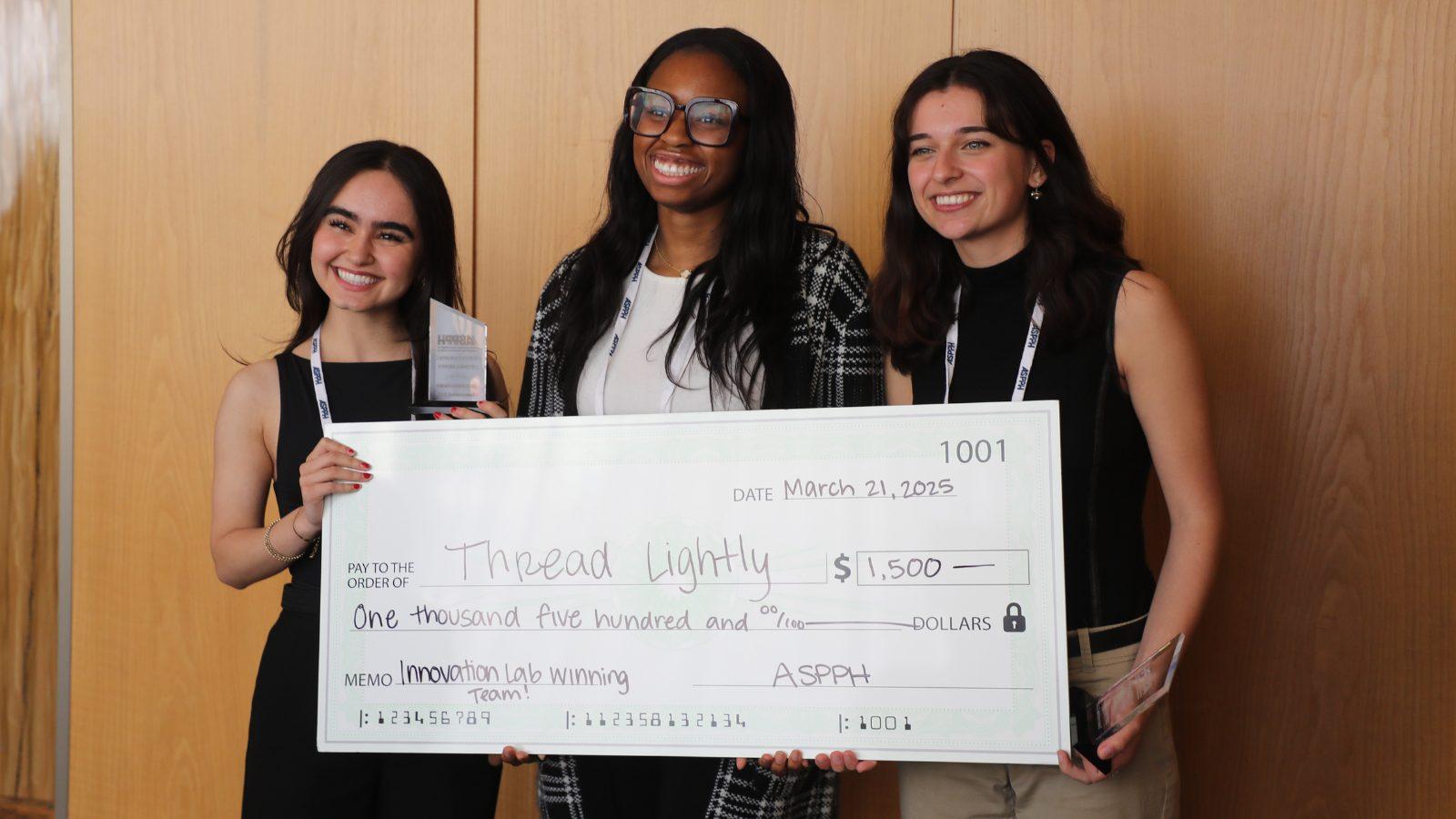 three students holding a giant money check