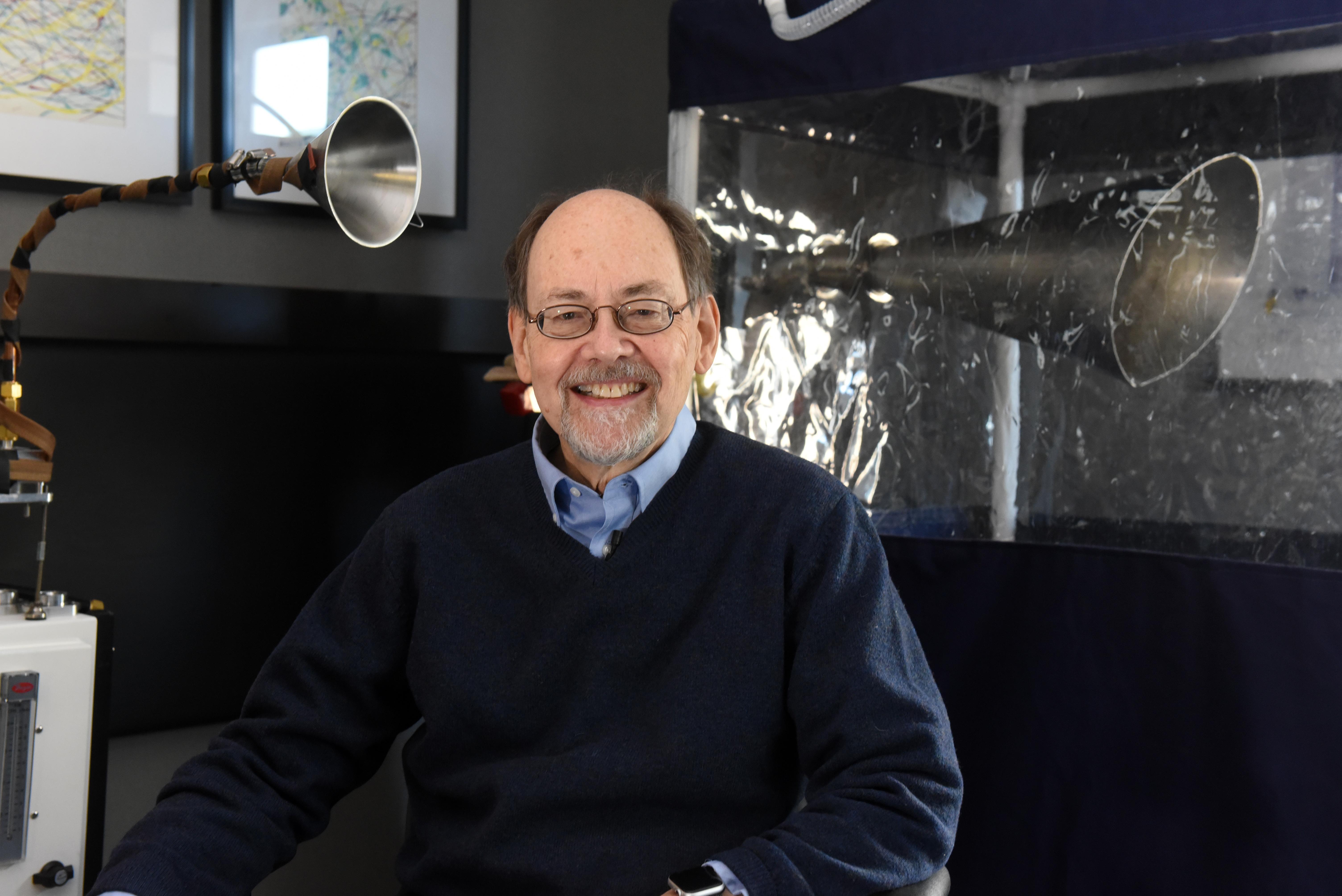 Dr Donald Milton smiles to camera in front of machine