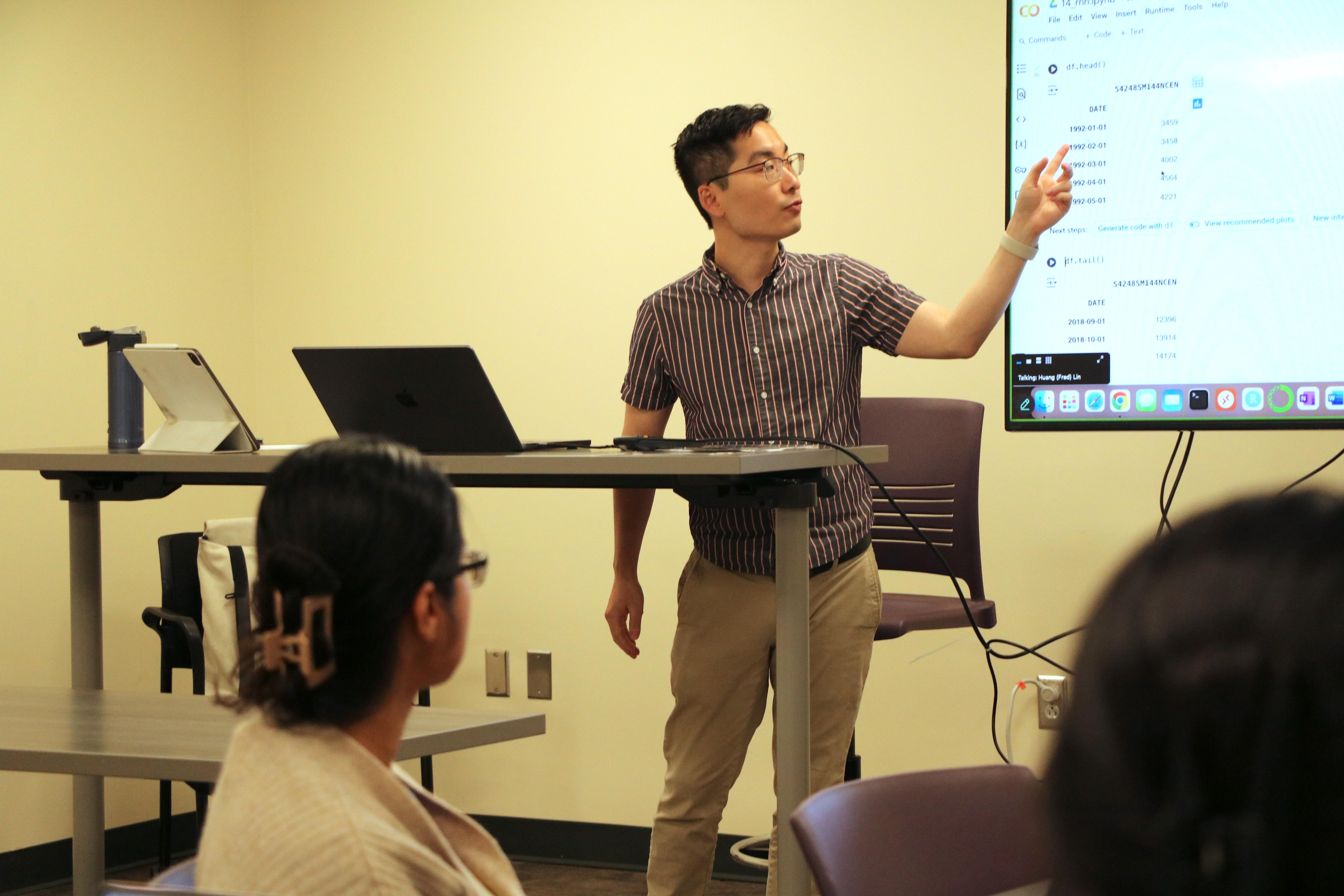 Dr Huang Lin teaching machine learning in a classroom, two students listen