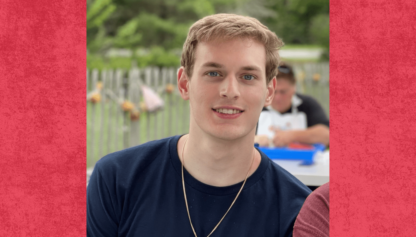white male student wearing dark t-shirt smiles to camera