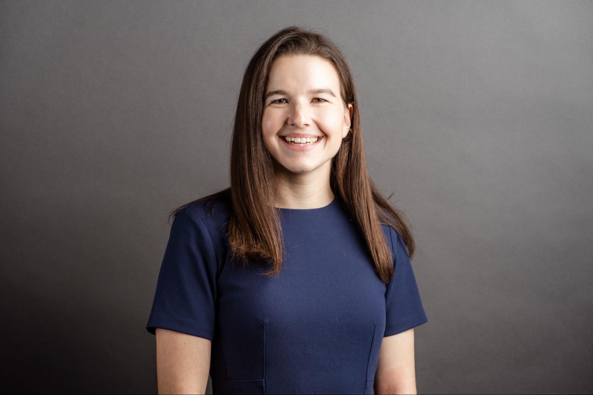 white woman in navy top with brown hair smiles at the camera