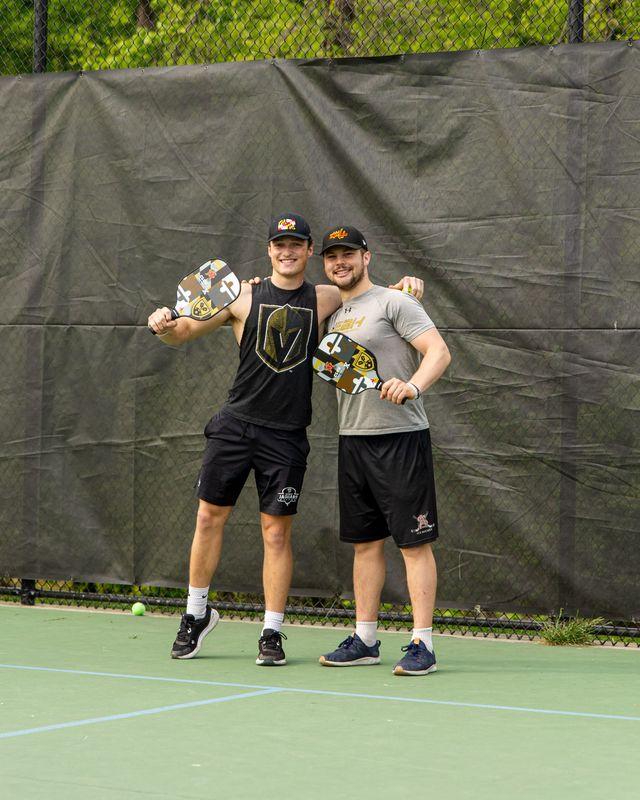 two students hold pickleball paddles
