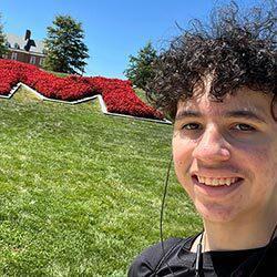 smiling male student headshot in front of UMD "M"