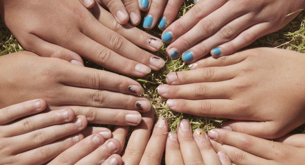 A group of diverse hands arranged in a circle on grass, symbolizing unity, collaboration, and community.