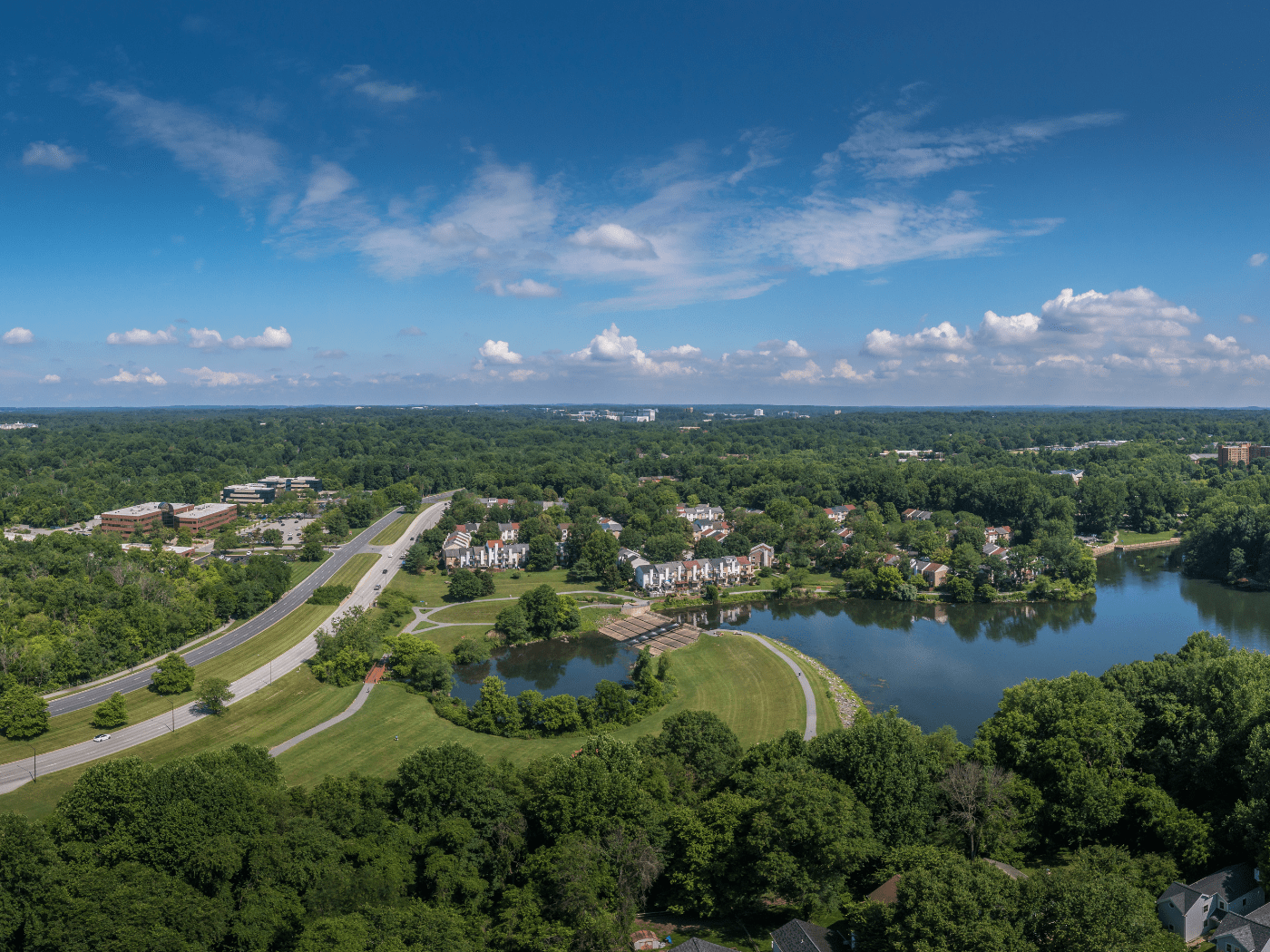 aerial view of rural town with pond and road and tree canopy