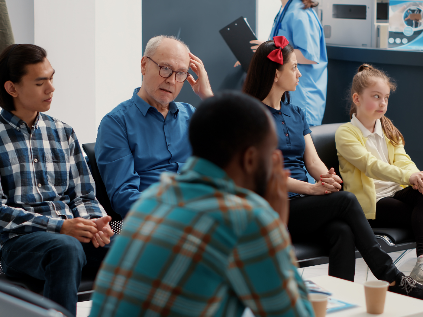 A diverse group of people sit in waiting room of a hospital