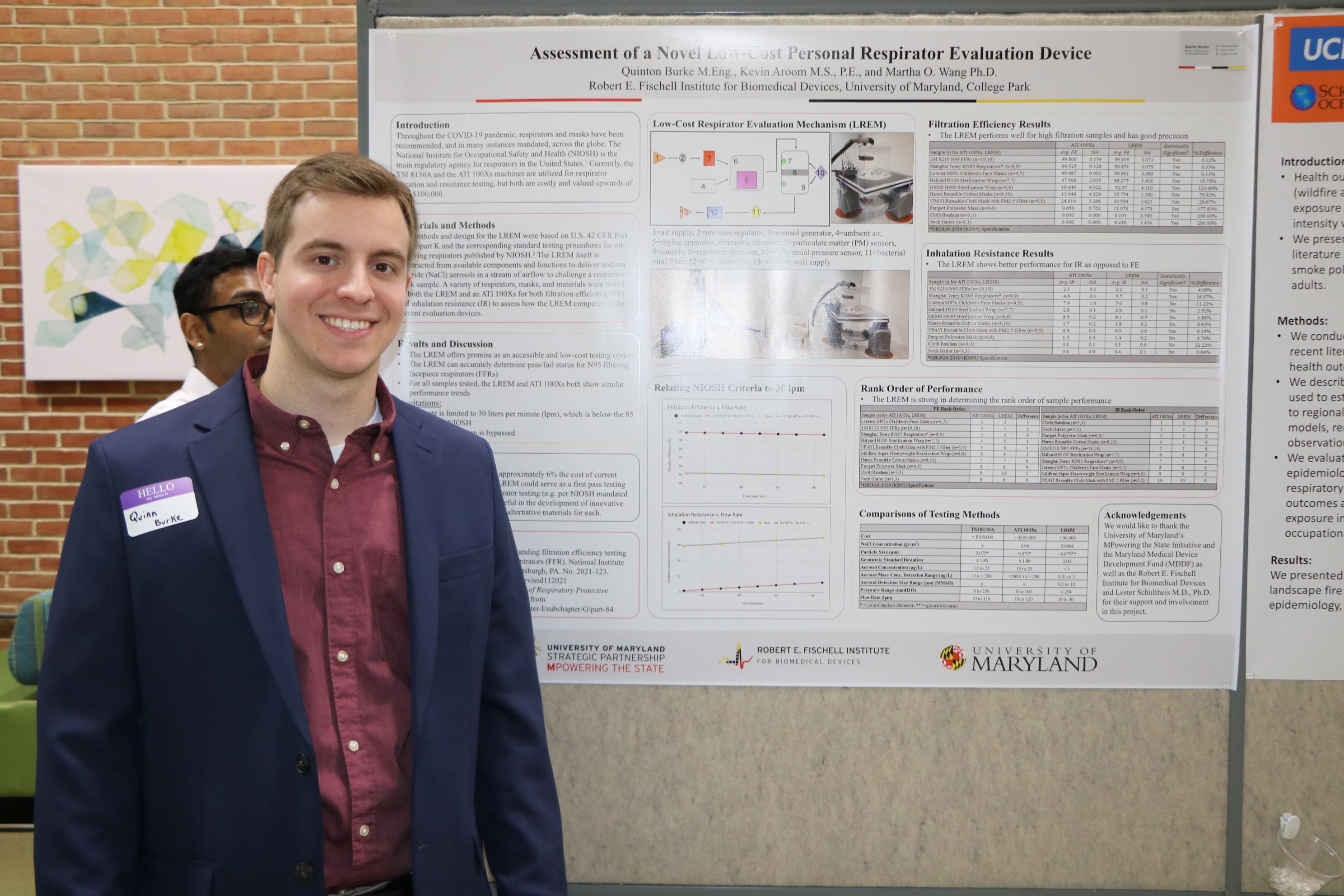 male student posing in front of his poster presentation