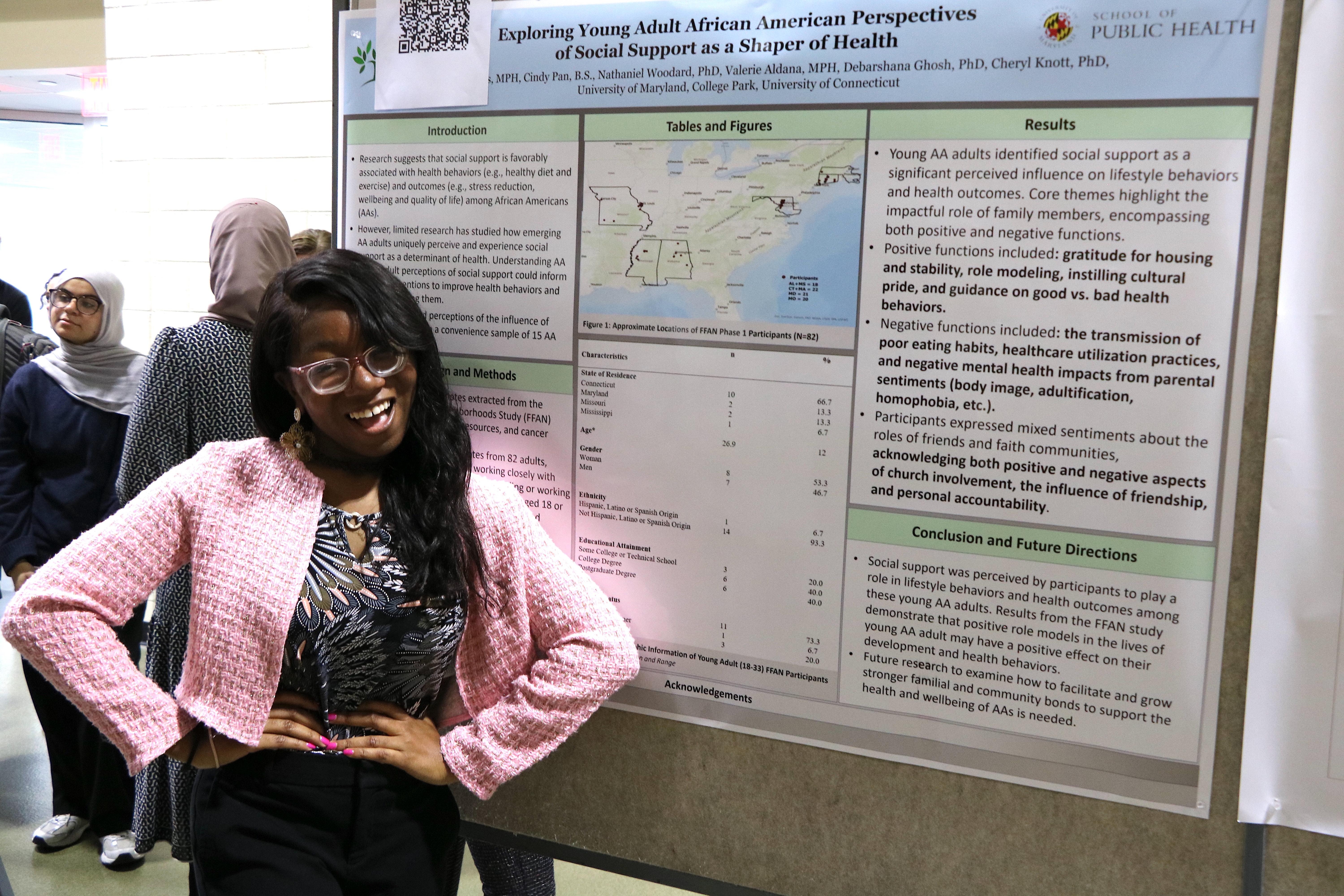 Female student posing in front of her poster presentation