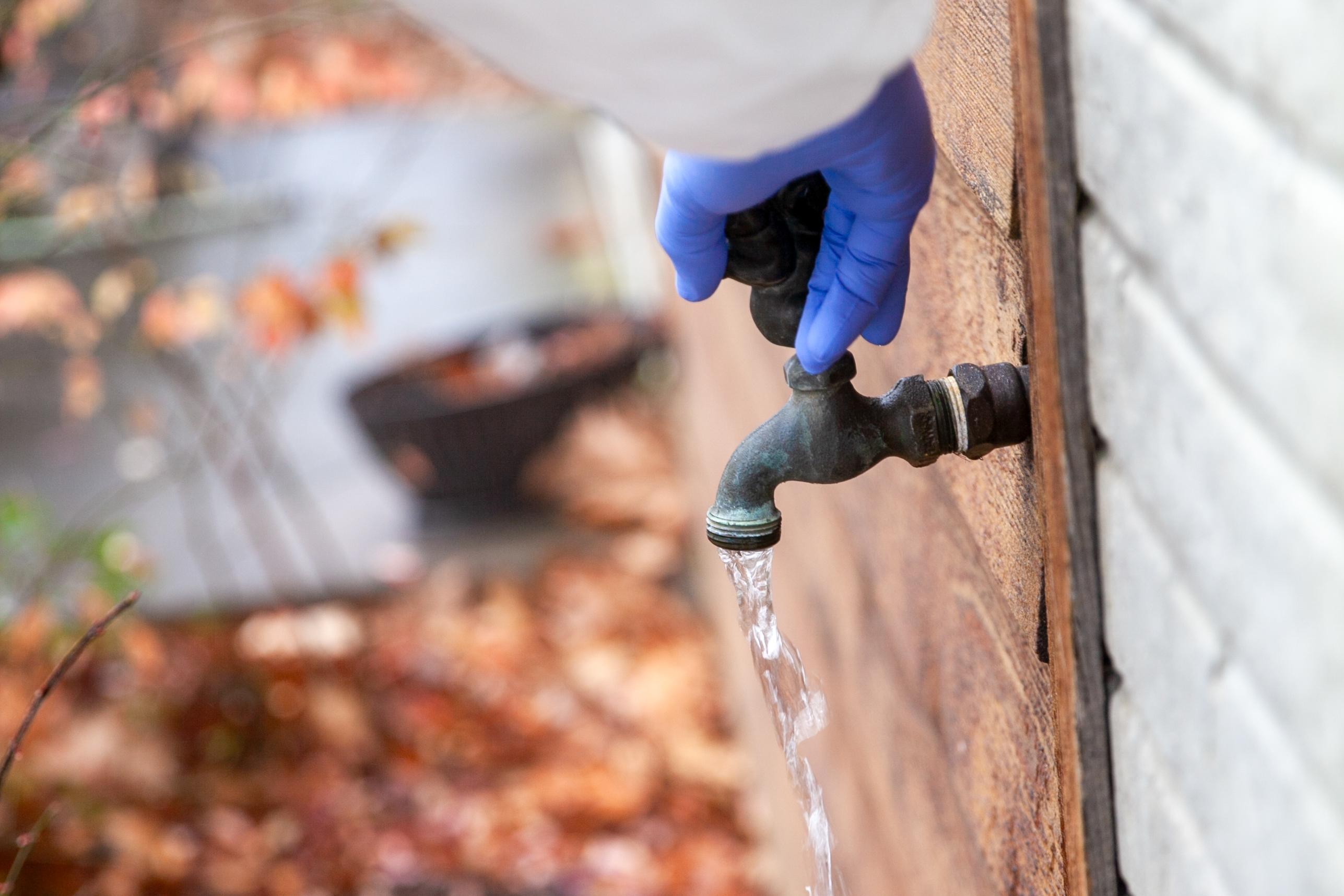 outside tap opened by a hand wearing sanitary glove