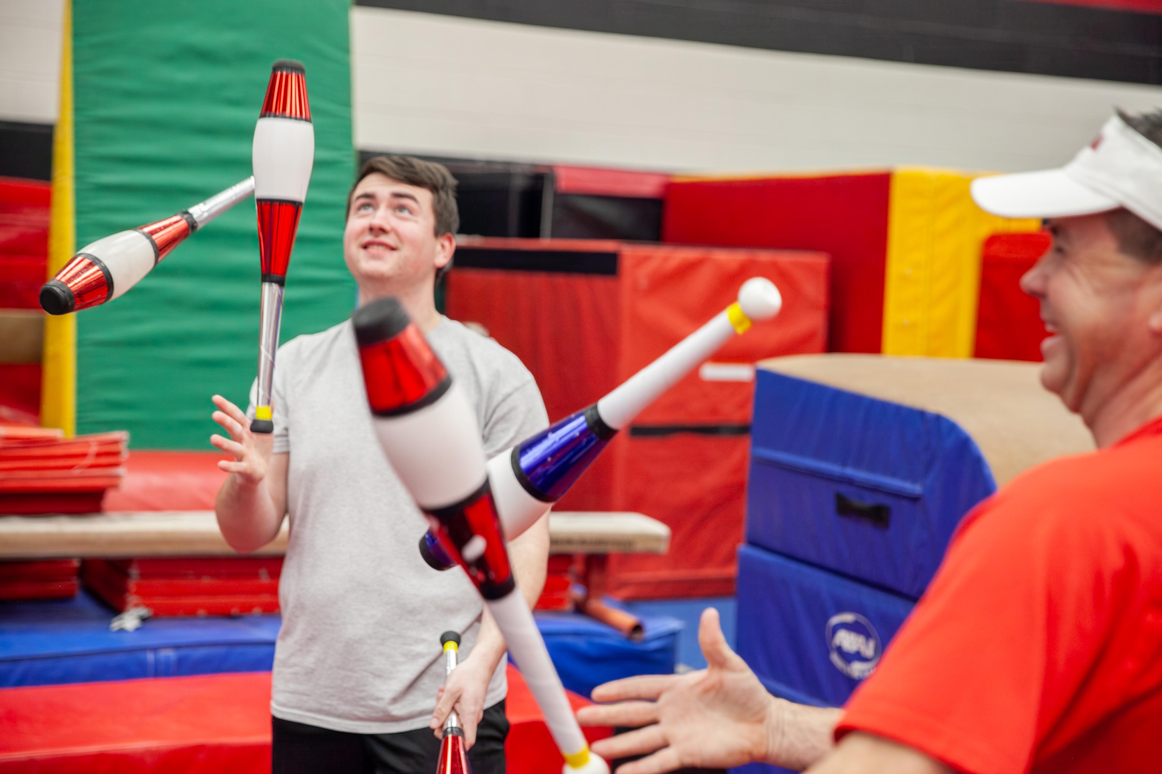 juggling pins in the air between father and son jugglers in the gymkana gym